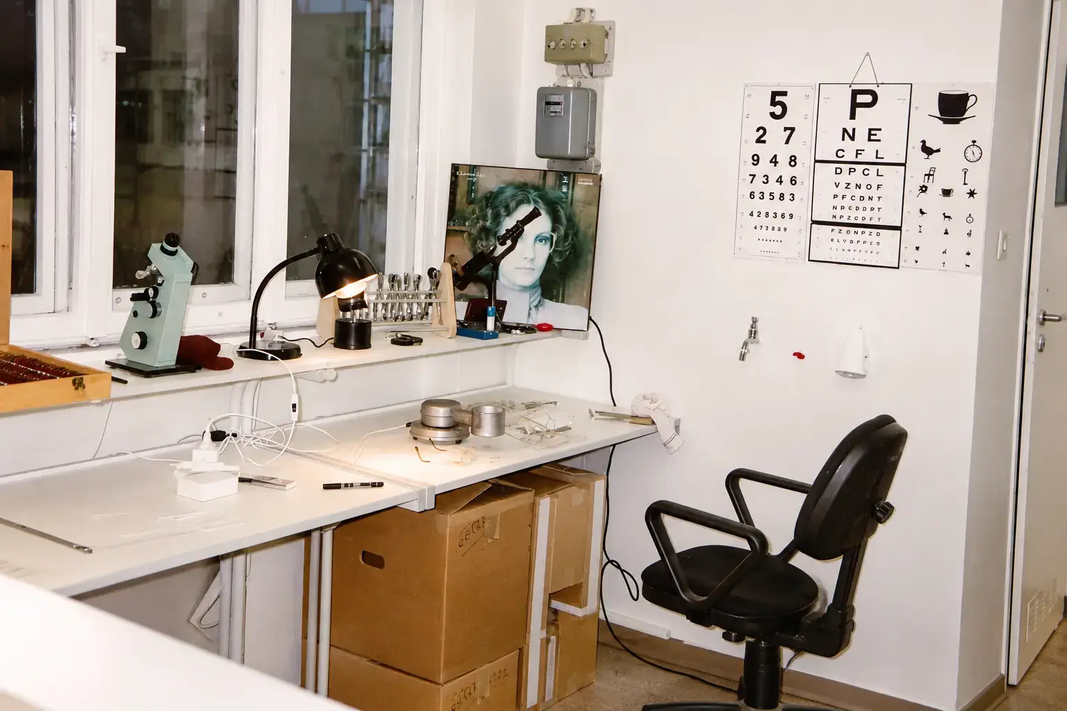Pracownia optyczna z mikroskopem, lampą i tablicami do badania wzroku