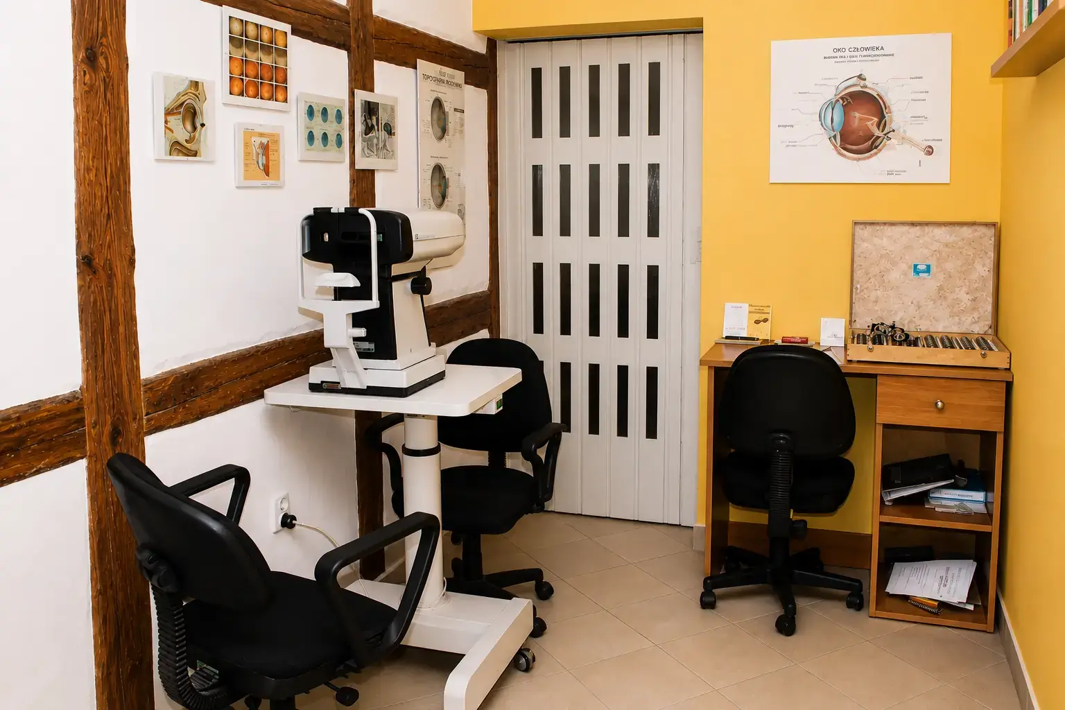 Nowoczesny gabinet optometryczny z autorefraktometrem, planszami anatomii oka i kasetą szkieł próbnych